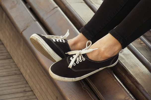 gambe femminili in sneakers in panchina - Foto, immagini