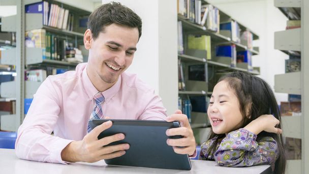 мужчина учитель и ребенок студент обучения и глядя на планшетное устройство
 - Фото, изображение