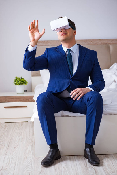 Uomo d'affari indossa un auricolare realtà virtuale in camera da letto - Foto, immagini