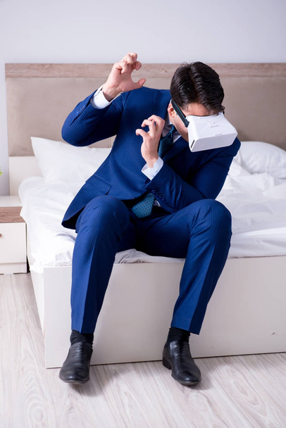 Hombre de negocios con un casco de realidad virtual en el dormitorio - Foto, Imagen