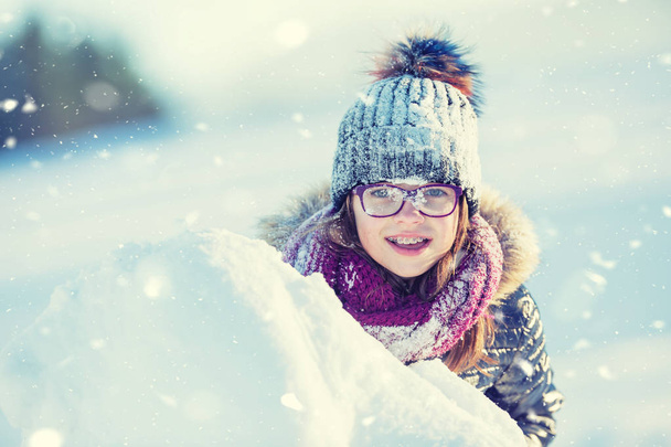 Young girl are playing with snow.Beauty Winter happy Girl Blowing Snow in frosty winter park or outdoors. Girl and winter cold weather - Foto, Imagem