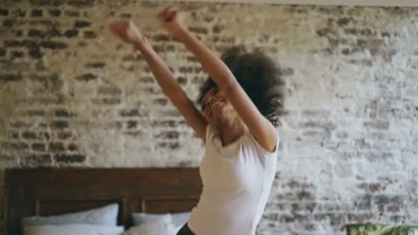 Attractive mixed race young joyful woman have fun dancing near bed at home - Materiał filmowy, wideo