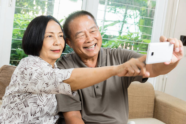 幸せな上級アジア カップルの笑顔とスマート フォンを使用して - 写真・画像
