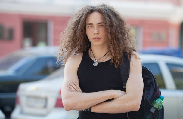 Outdoor portrait of modern young man walk street. Man with long curly hair. - Photo, Image