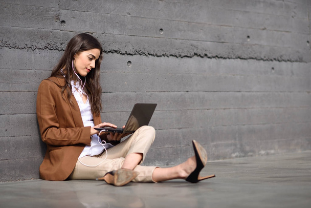Jeune femme d'affaires assise sur le sol regardant son ordinateur portable compu
 - Photo, image