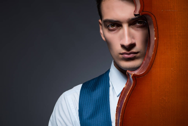 Young man playing cello in dark room - Fotó, kép
