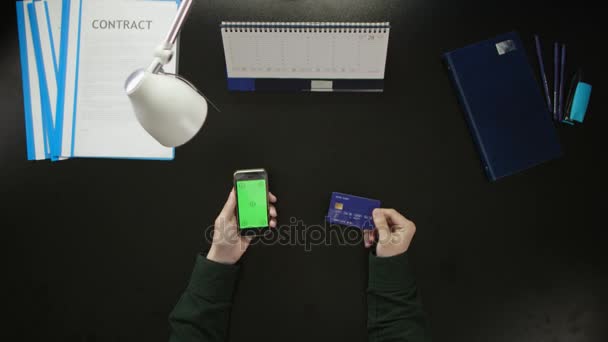 Egy férfi ül egy íróasztal, és a telefon használata. - Felvétel, videó