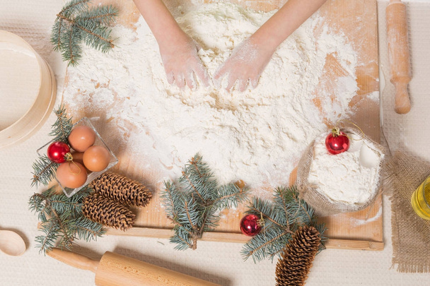 las manos de la niña amasan la masa, la harina y los ingredientes para la galleta de Navidad
 - Foto, imagen