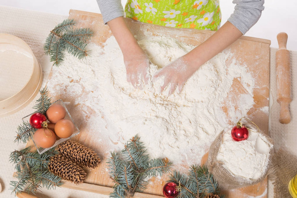 as mãos da menina amassar a massa, a farinha e os ingredientes para o biscoito de Natal
 - Foto, Imagem