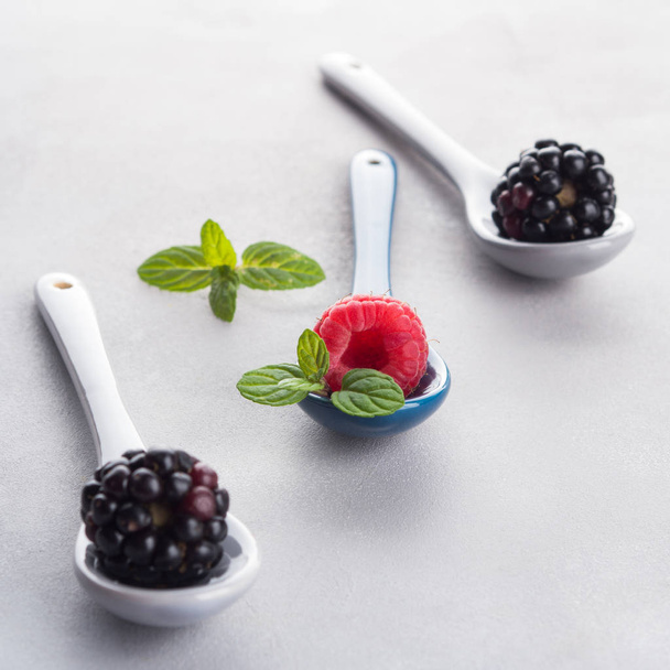 Fresh berries on spoons on gray background - Photo, image