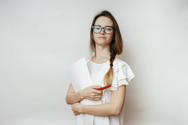 cute young girl wearing glasses and a white t-shirt holding documents, posing, looking at camera - Fotó, kép