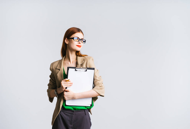 stylish pensive girl with glasses, with red lipstick holds a folder with documents, looks aside - Foto, Bild