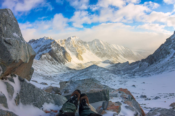 First person view to legs in crampons take a rest on the top of mountain - Foto, Bild
