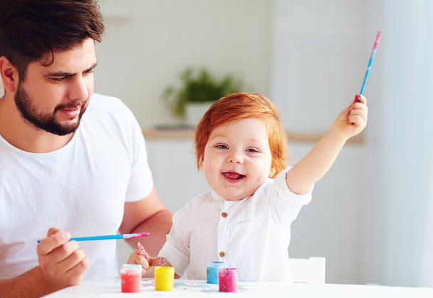 mutlu küçük bebek sanatçı renkli boyalar ve babası evde ile çizim - Fotoğraf, Görsel
