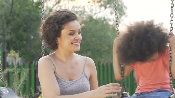 Jolie mère balançant sa fille bien-aimée dans la cour, bonheur familial
 - Séquence, vidéo