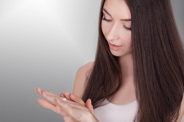 Hermosa mujer joven que aplica crema facial a su pómulo en un
 - Foto, imagen