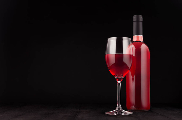 Bottle of rose wine and wine glass mock up on elegant dark black wooden background, copy space.  - Photo, image