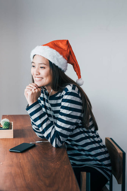Asian teenage girl wear santa hat and smile face resting her chi - 写真・画像