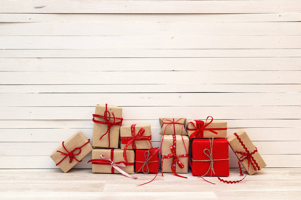 Gift boxes with red ribbons on white wooden background. Copy spa - 写真・画像