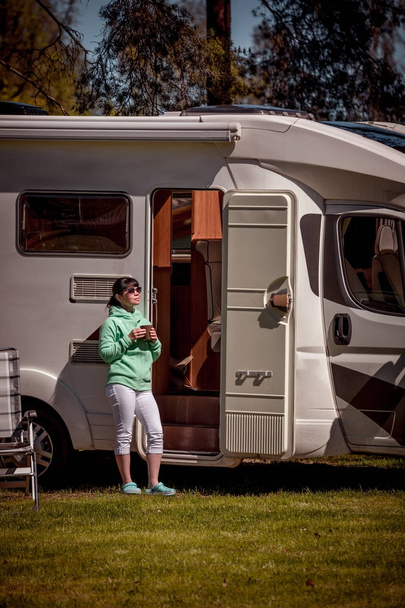 Woman is standing with a mug of coffee near the camper RV. - Fotoğraf, Görsel