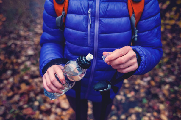 A woman with a backpack opens a bottle of water. - Photo, Image