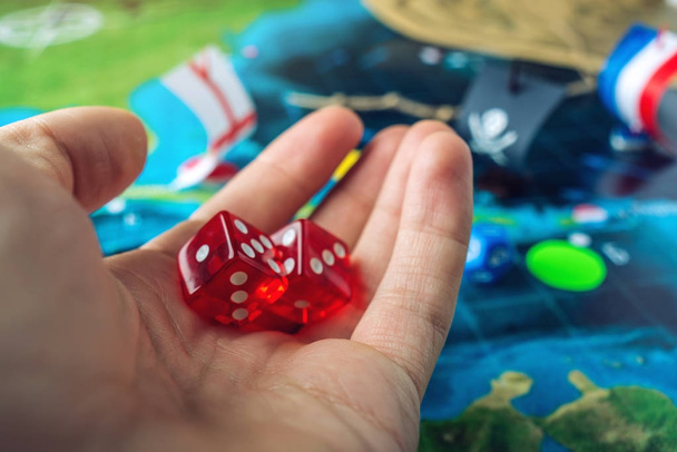 Mano tirando dados rojos en el mapa del mundo de los juegos de mesa hechos a mano campo de juego con un barco pirata
 - Foto, imagen