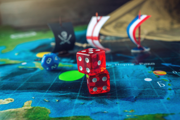 Красные играющие кости на карте мира полевых настольных игр ручной работы с пиратским кораблем
 - Фото, изображение