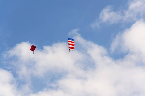 Dois pára-quedistas paraquedismo com nuvens de paraquedas coloridas azul céu fundo
 - Foto, Imagem