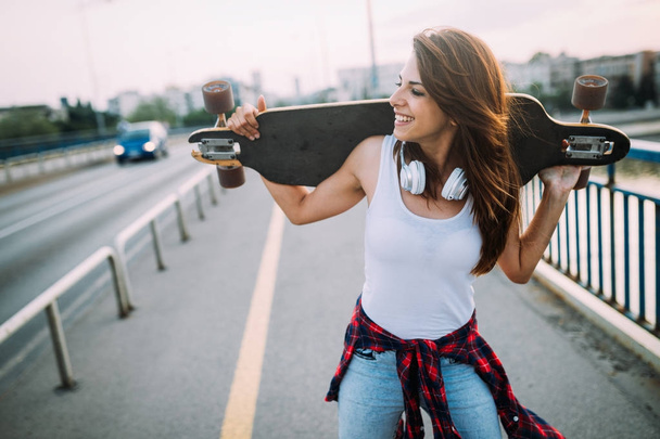  smiling girl carrying skateboard - Fotó, kép