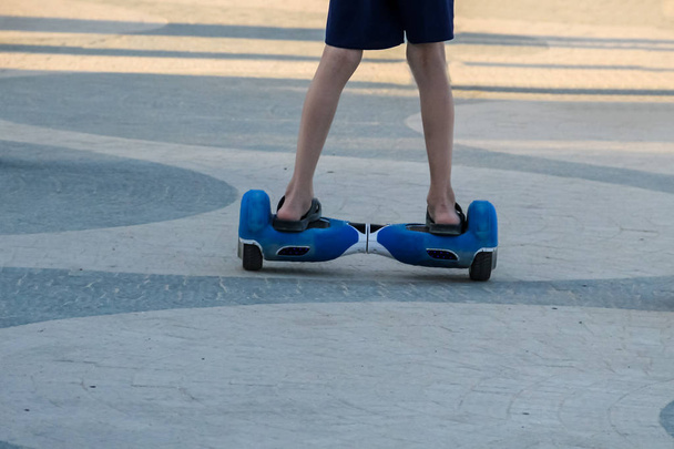 Pernas de menino montando em auto-equilíbrio mini hoverboard no parque da cidade
 - Foto, Imagem