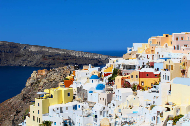 Santorini Landscape - Super colourful Oia city houses panoramic view with a blue sky and mountains in background - Valokuva, kuva