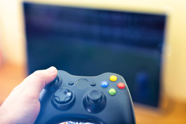 Mão segurando controle de console de jogo jogando jogo de esporte no t
 - Foto, Imagem