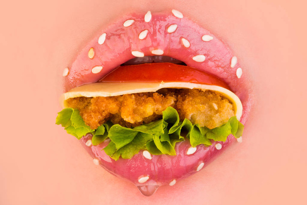 leckeres Sandwich. Sandwich im Appetit Mund. weibliche Lippen mit Sesam. Tomaten, Gemüse, Käse und Collette in Frauenlippen. Nahrungsverführung. süße rosa Lippen. Mundkreis - Foto, Bild