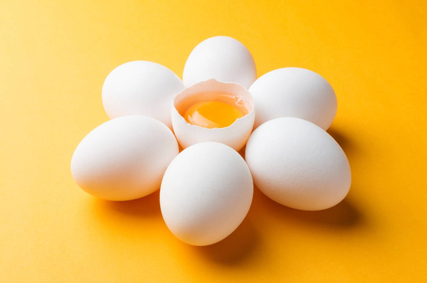Ovos brancos e gema de ovo no fundo amarelo
 - Foto, Imagem