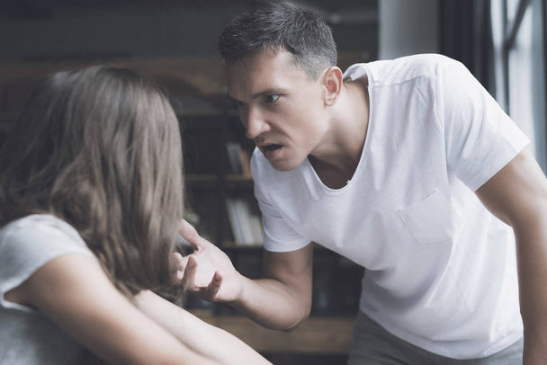 Un homme en t-shirt blanc regarde avec colère la petite fille aux cheveux bruns
 - Photo, image