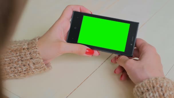 Vrouw op zoek naar smartphone met groen scherm - Video