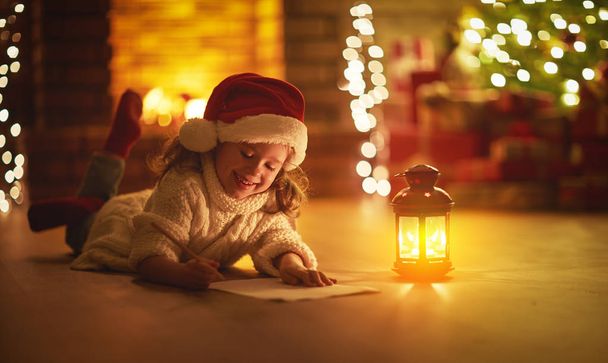 child girl writing letter santa home near Christmas tree - Foto, afbeelding
