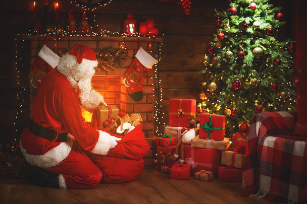 Joyeux Noël ! santa claus près de la cheminée et l'arbre avec gi
 - Photo, image