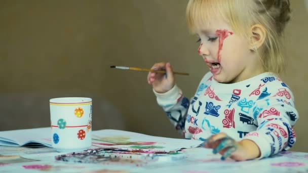 Αργή κίνηση: όμορφο κορίτσι των τριών χρόνων ζωγραφίζει σε ένα άλμπουμ σε ένα τραπέζι στο σπίτι. - Πλάνα, βίντεο
