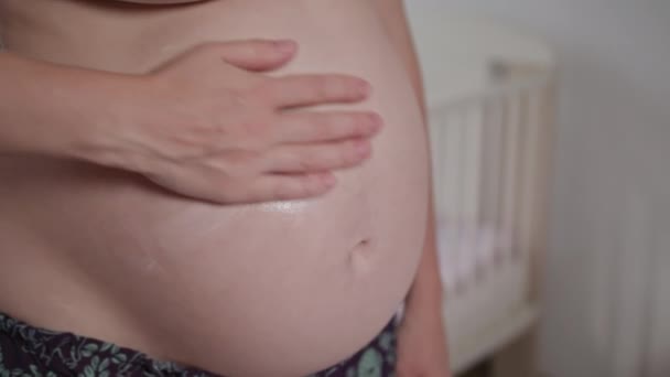 Nuori raskaana oleva nainen hieroo kermaa vatsaansa
 - Materiaali, video