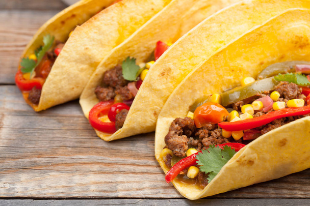 Three Mexican tacos with minced beef and mix vegetables on old rustic table. Mexican dish with sauce salsa in bowl and avocado. Spicy and hot street food. Close-up - Photo, image