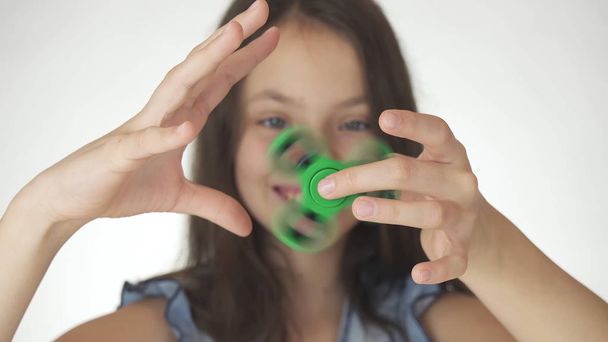 Hermosa chica adolescente alegre jugando con verde fidget spinner sobre fondo blanco
 - Foto, imagen