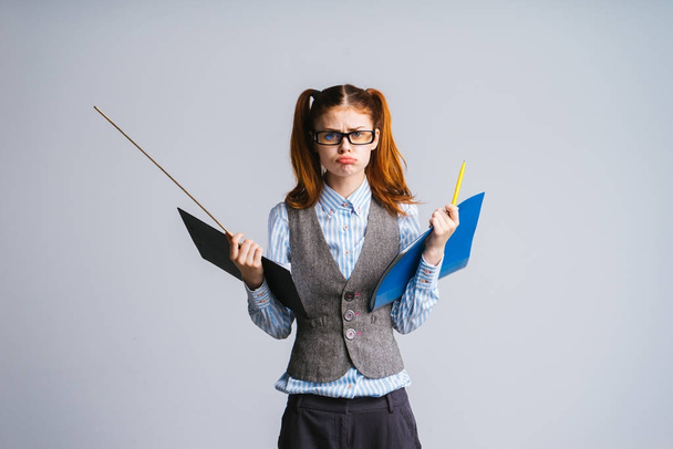 sad red-haired schoolgirl with glasses holds folders with documents and ruler - Foto, Imagen