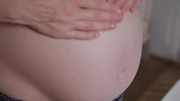 młoda kobieta w ciąży ściera krem na brzuchu - Materiał filmowy, wideo