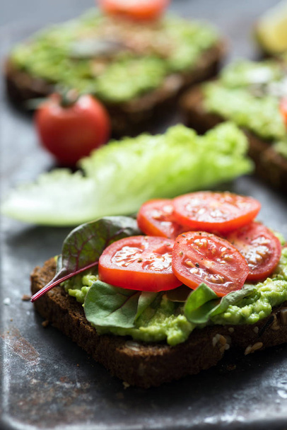 Vegan toast with avocado, spinach and tomato. Closeup view - Photo, Image