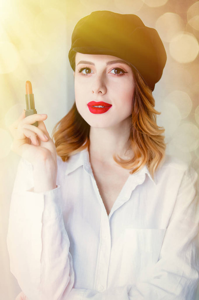 Svislý řez portrét mladé sebevědomá žena v klobouku drží rtěnka pro make-up pózuje na rozostření pozadí s bokeh - Fotografie, Obrázek