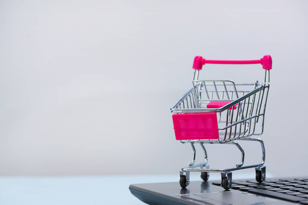 Shopping cart or supermarket trolley with laptop notebook on gre - 写真・画像