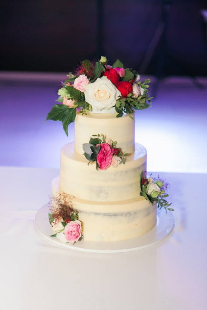 Restoranda masaya çiçek ile beyaz düğün pastası - Fotoğraf, Görsel