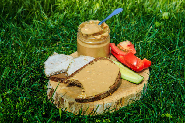spoonful of peanut butter on wooden plate with meat sandwiches - Foto, afbeelding
