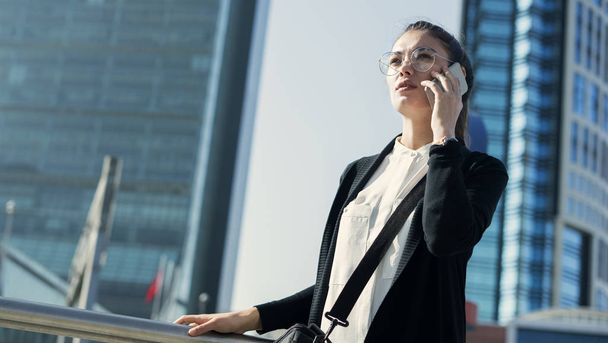 Бізнес-леді говорить мобільний телефон на відкритому повітрі
 - Фото, зображення